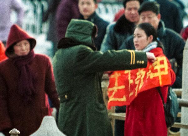 A woman who holds up a Falun Gong banner is detained by police at Beijing's Tiananmen Gate in China, on Jan. 25, 2001. (AP Photo/Greg Baker)