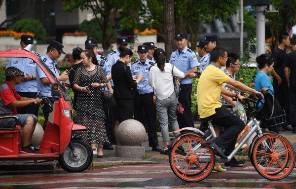 Police check the identification of passersby as they search for petitioners near China's Banking Regulatory Commission in Beijing on Aug. 6, 2018. (Greg Baker/AFP via Getty Images)