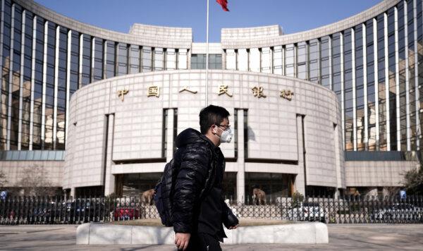 A man wearing a mask walks past the headquarters of the People's Bank of China, the central bank, in Beijing, China, on Feb. 3, 2020. (Jason Lee/Reuters)