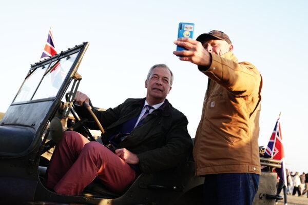 A man takes a selfie with the leader of Reform UK Nigel Farage (L) on Gold Beach in Arromanches, Normandy, France, on June 6, 2024. (Aaron Chown/PA Wire)
