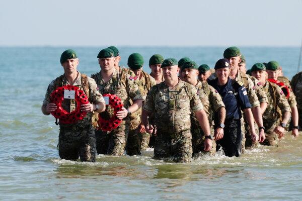 Royal Marines of 47 Commando and civilians commemorate the 80th anniversary of the D-Day landings by landing at a beach at Asnelles in Normandy, France, on June 6, 2024. (Aaron Chown/PA)