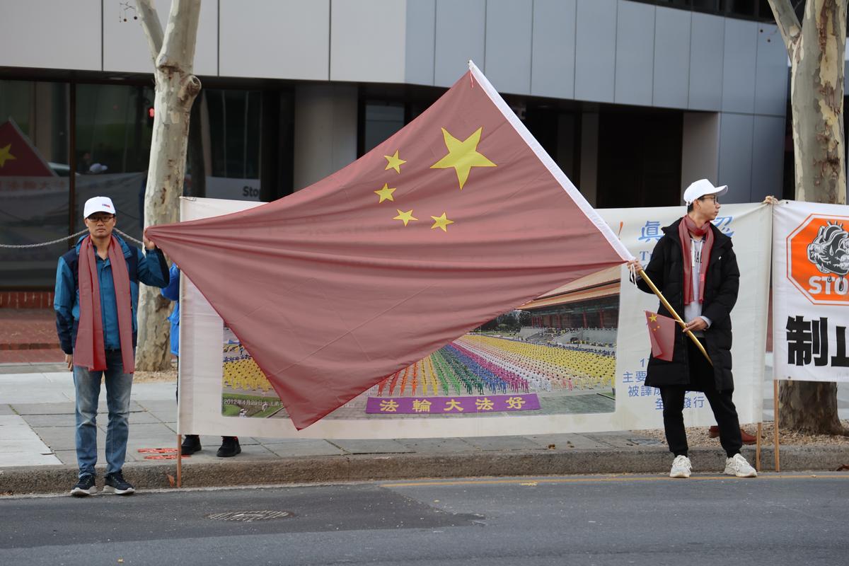Pro-CCP supporters attempting to obscure a banner that describes the peaceful meditation practice Falun Gong, which is currently being persecuted in China by the Chinese Communist Party, taken in Adelaide, Australia on June 15, 2024. (Yangyang Lu/NTD Television)