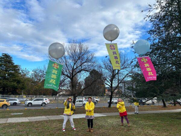 Falun Gong practitioners fly balloons carrying their messages to counter pro-CCP protesters's attempts to block their banners from view in Canberra, Australia, on June 17, 2024. (The Epoch Times)