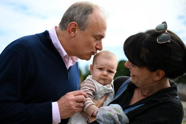 Leader of the Liberal Democrats Ed Davey kisses 3-month-old baby Nellie Timpson prior to making sandcastles at Broadsands Beach, in Paignton, England, on June 17, 2024. (Finnbarr Webster/Getty Images)