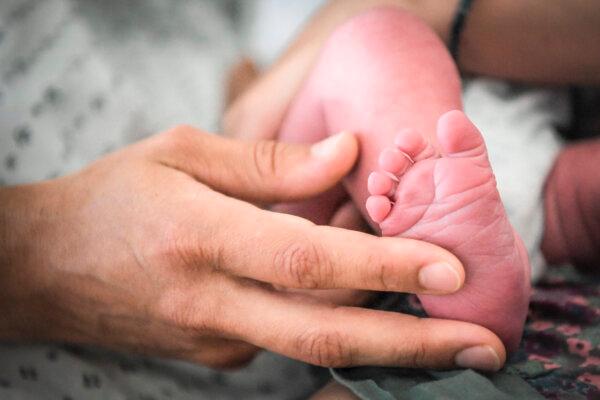 A woman holds the foot of a baby in a file photo. (Loic Venance/AFP via Getty Images)