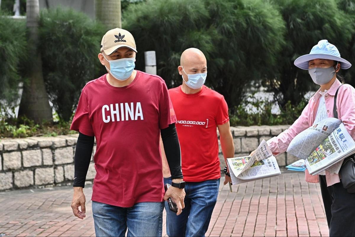 On Oct. 31, 2022, on the day he was sentenced, Hu Aimin (C) passed by a Falun Gong practitioner who distributed “Minghui Weekly.” File photo. (Sung Pi-lung/The Epoch Times)