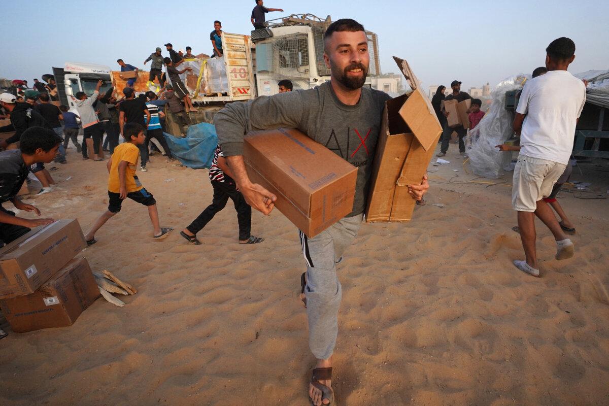 Palestinians carry boxes of humanitarian aid after rushing trucks from the U.S.-built Trident Pier near Nuseirat, in the central Gaza Strip, on May 18, 2024. (AFP via Getty Images)