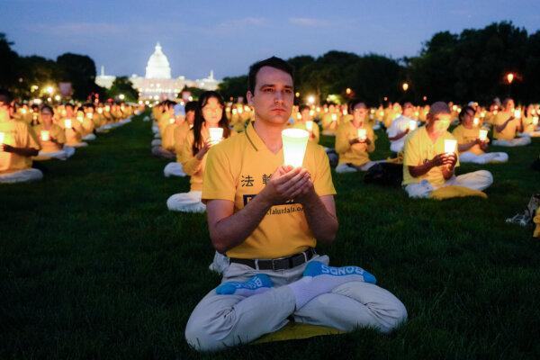 Falun Gong practitioners take part in a candlelight vigil in memory of Falun Gong practitioners who died during 25 years of ongoing persecution by the Chinese Communist Party in China at the National Mall in Washington on July 11, 2024. (Larry Dye/The Epoch Times)