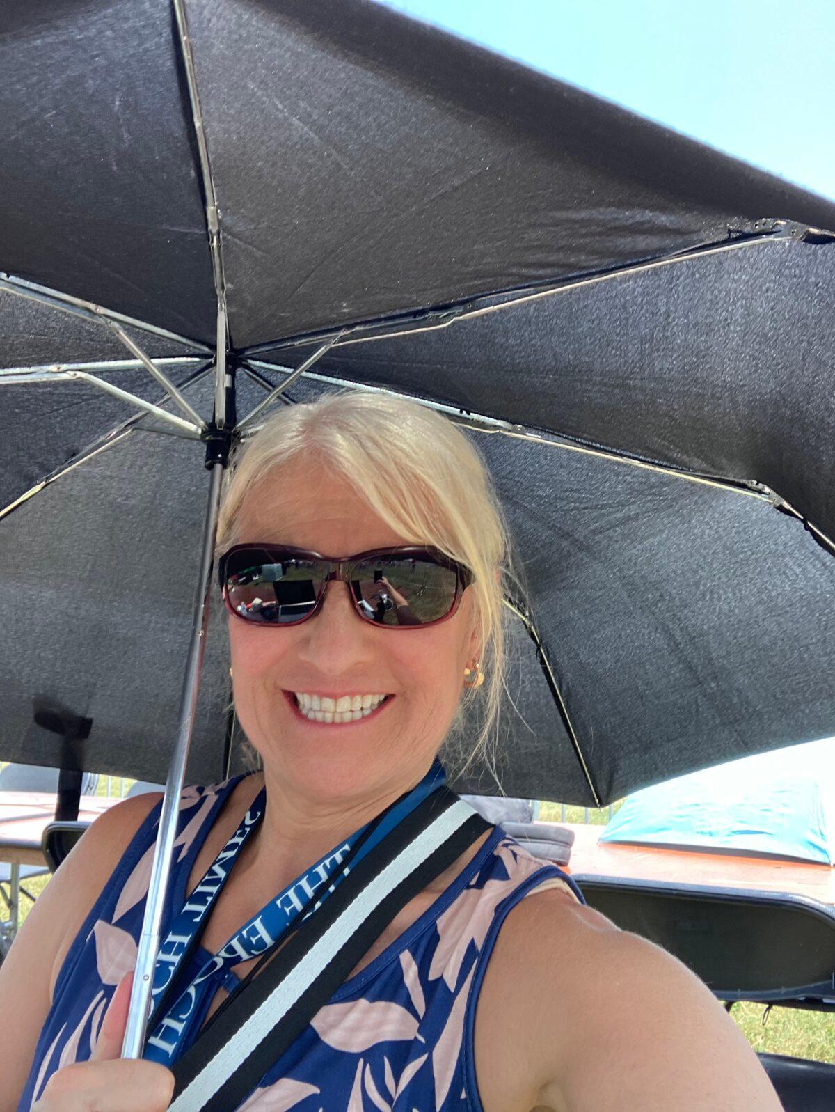 Epoch Times reporter Janice Hisle uses an umbrella to shield her on a hot day while reporting on the Trump rally in Butler, Pennsylvania, hours before an assassination attempt on July 13, 2024. (Janice Hisle/The Epoch Times)