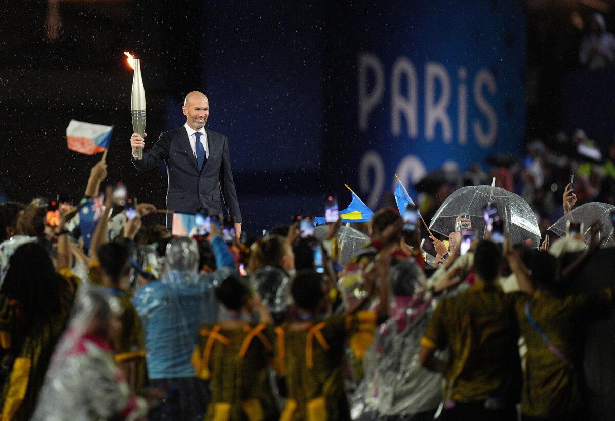 Former French football player Zinedine Zidane holds the Olympic torch during the opening ceremony of the Paris 2024 Olympic Games in Paris, France, on July 26, 2024. (Xu Chang-Pool/Getty Images)