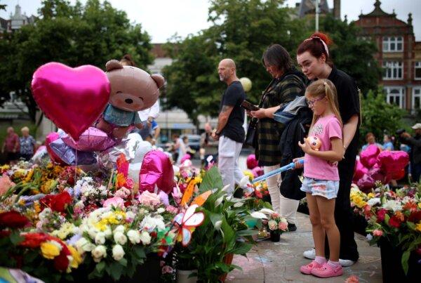 Members of the public lay and look at floral tribute left outside the Town Hall in Southport, ahead of a vigil, in memory of three children killed in a knife attack, on Aug. 5, 2024. (Ryan Jenkinson/PA Wire)
