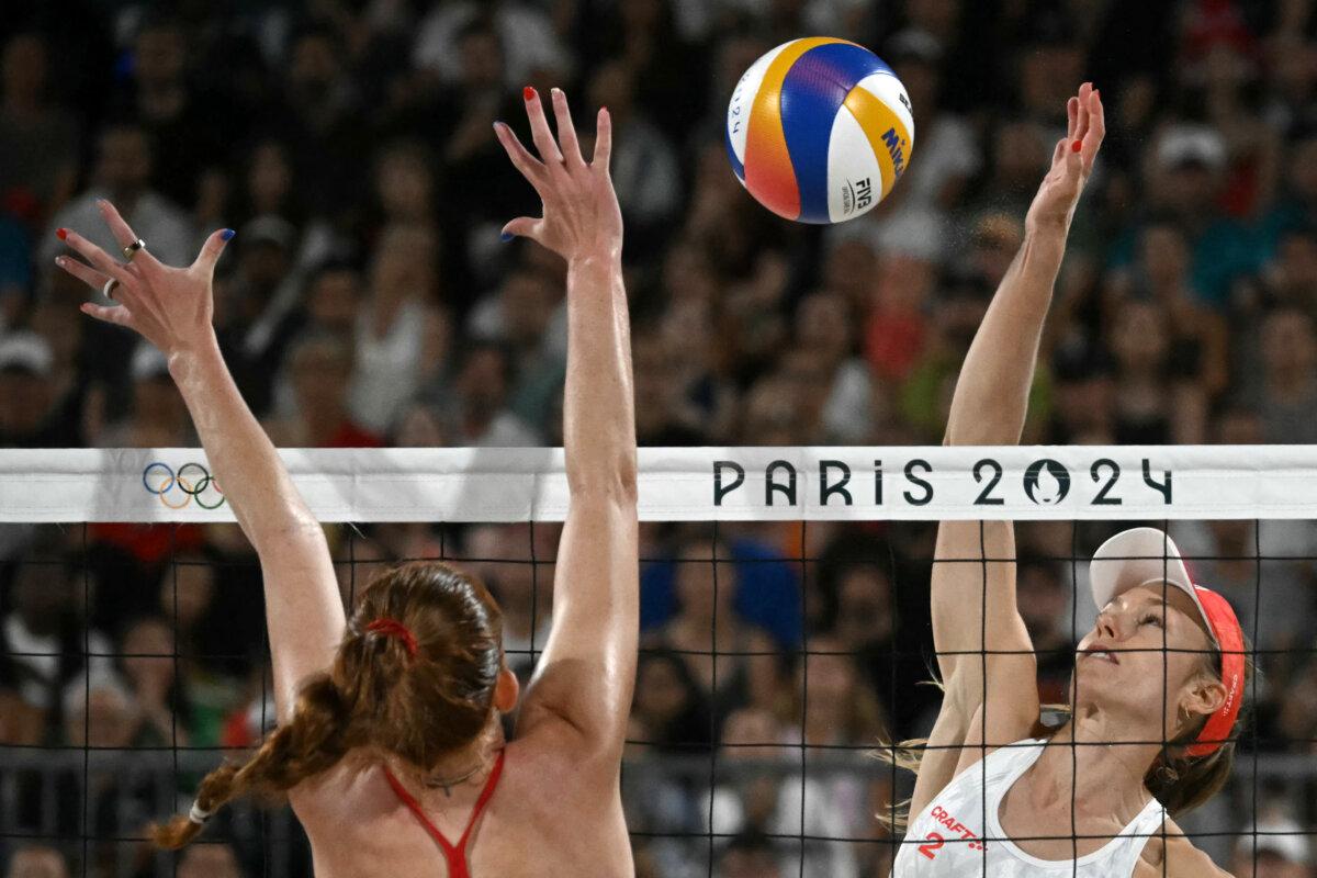 Switzerland's Nina Brunner spikes the ball as United States' Kelly Cheng blocks in the women's quarterfinal beach volleyball match between USA and Switzerland during the Olympic Games at the Eiffel Tower Stadium in Paris on Aug. 6, 2024. (Carl De Souza/AFP via Getty Images)
