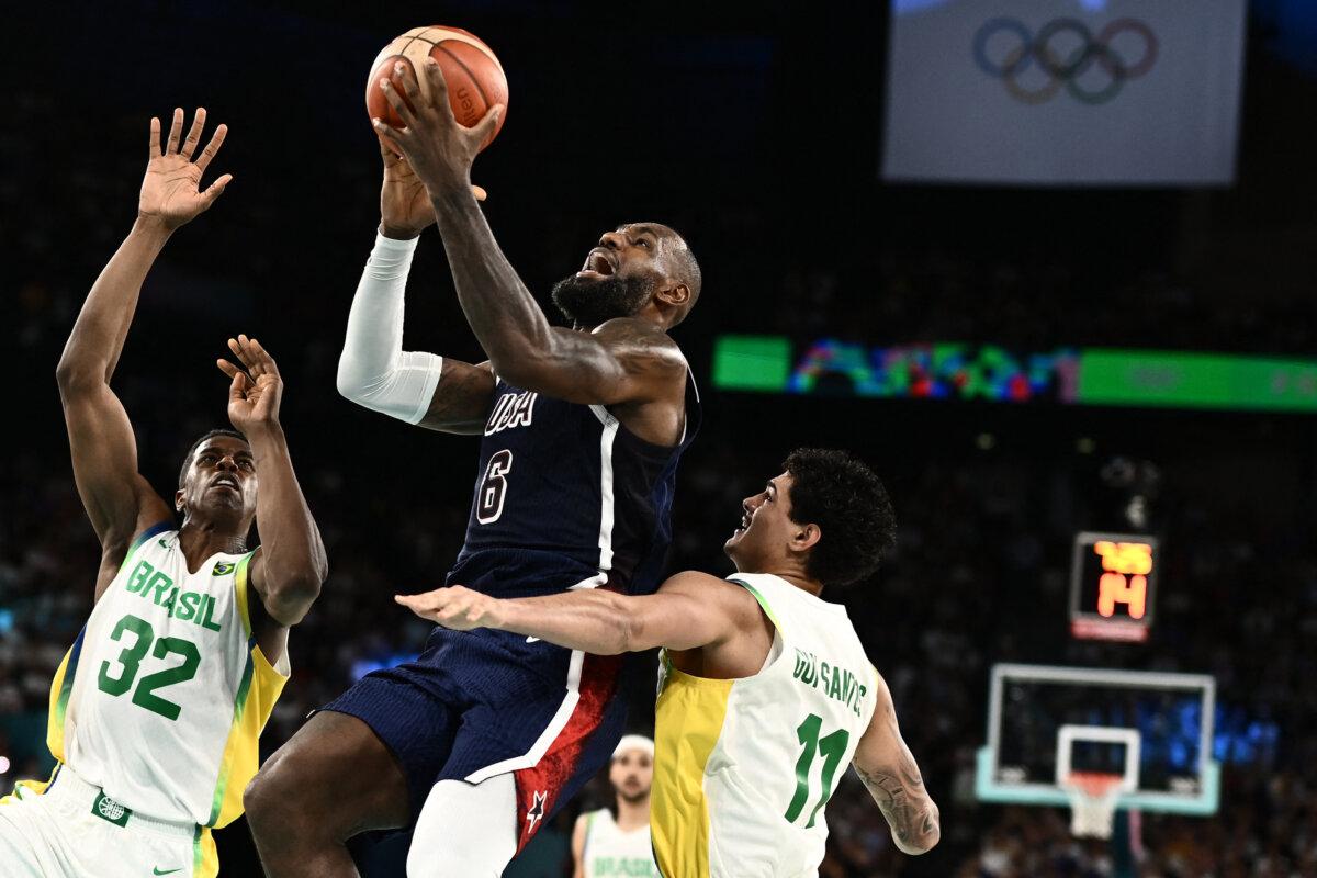 Team USA's LeBron James goes to the basket next to Brazil's Georginho De Paula and Brazil's Gui Santos in the men's quarterfinal basketball match between Brazil and the USA during the Olympic Games at the Bercy Arena in Paris on Aug. 6, 2024. (Aris Messinis/ AFP via Getty Images)