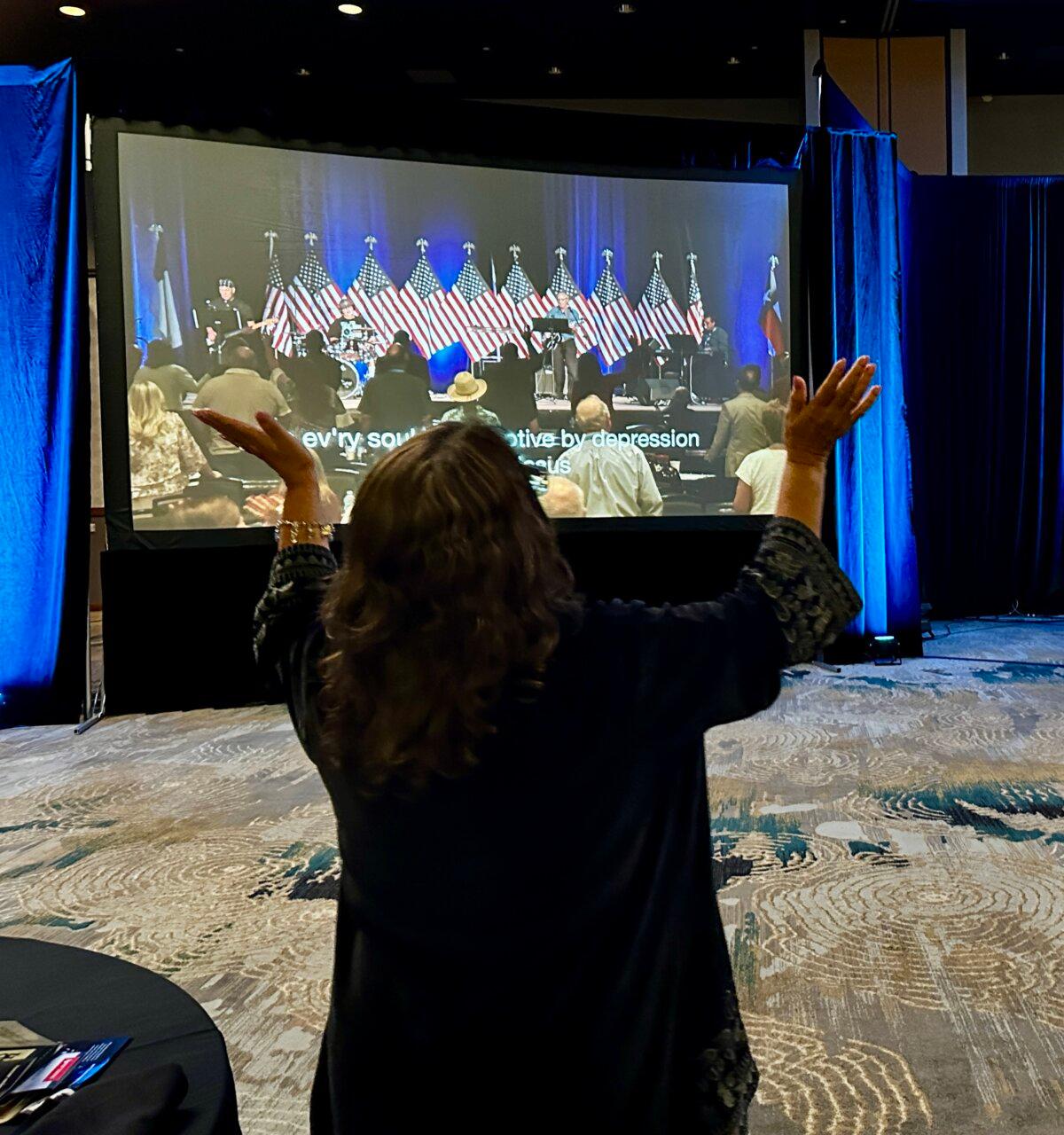 A woman at a Remnant Alliance conference raises her hands in praise to God in Frisco, Texas, on Aug.2, 2024. (Darlene McCormick Sanchez/The Epoch Times)