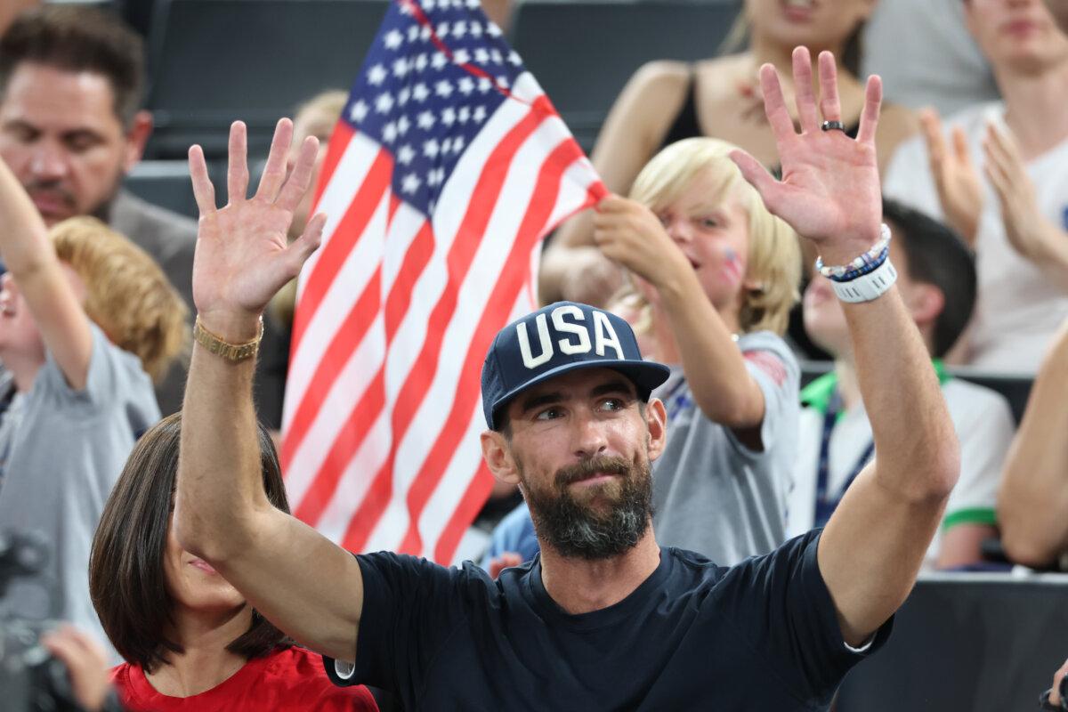 Former American swimmer Michael Phelps waves to fans during a women's basketball quarterfinal game between Team United States and Team Nigeria on day 12 of the Olympic Games at Bercy Arena in Paris on Aug. 7, 2024. (Pascal Le Segretain/Getty Images)