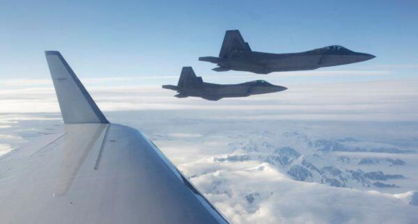 A pair of U.S.-built NORAD F-22 fighter jets fly off the wing of a civilian airplane playing the role of a hijacked airliner over a mountainous area of Alaska, on Aug. 10, 2010. (AP Photo/Ted S. Warren)
