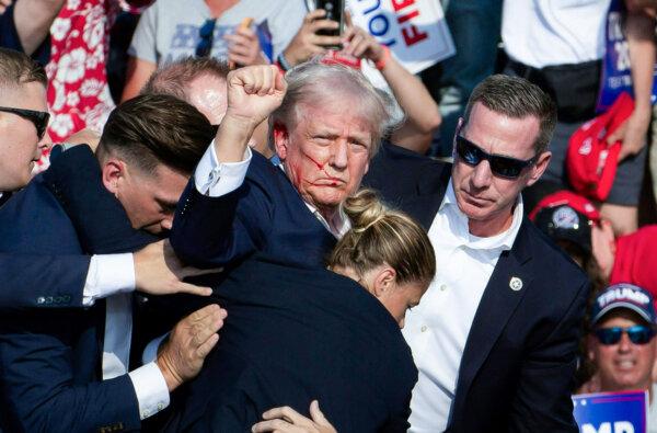 Former President Donald Trump, with blood on his face, is surrounded by Secret Service agents after being shot by would-be assassin Thomas Crooks at Butler Farm Show Inc. in Butler, Pa., on July 13, 2024. (Rebecca Droke/AFP via Getty Images)