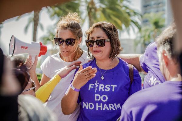 Erin Friday (L) comforts Abigail Martinez (R), the mother of a transgender teen who committed suicide, while transgender activists block TV cameras from capturing her story in Anaheim on Oct. 8, 2022. (John Fredricks/The Epoch Times)