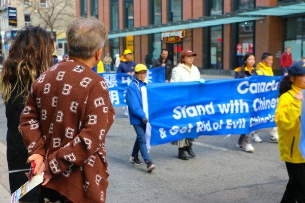 People watch a parade in downtown Toronto on Nov. 2, 2024, marking the 20th anniversary of the release of "Nine Commentaries on the Communist Party," a book that details the Chinese regime's totalitarian rule and human rights abuses. (The Epoch Times)