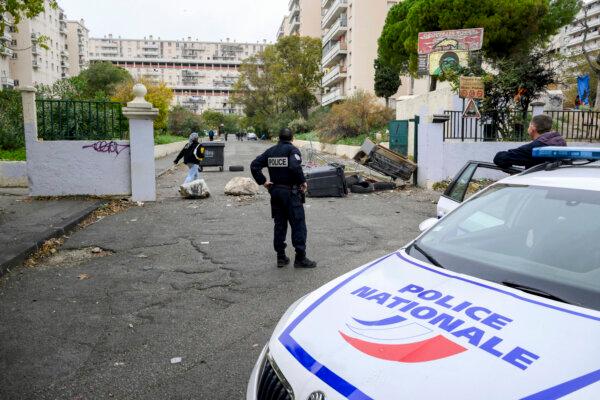 A Police officer from the BST 14 Brigade, specializing in drug trafficking, stands next to a barricade at the entrance of Les Rosiers housing project in the northern districts of Marseille, France, on Dec. 1, 2023. (Nicolas Tucat / AFP via Getty Images)