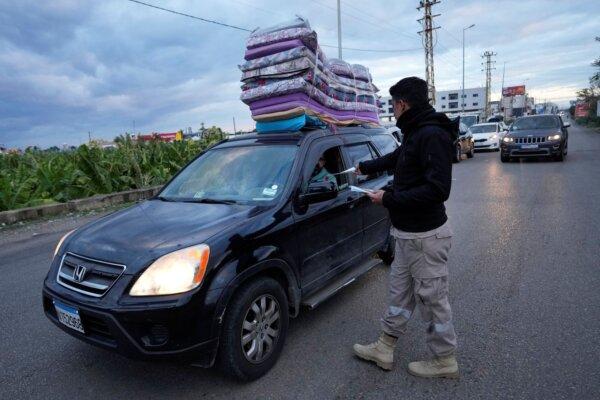 A civil defense worker distributes safety pamphlets to people returning back to their villages after the ceasefire between Hezbollah and Israel began, in Tyre, south Lebanon, on Nov. 27, 2024. (Hussein Malla/AP)