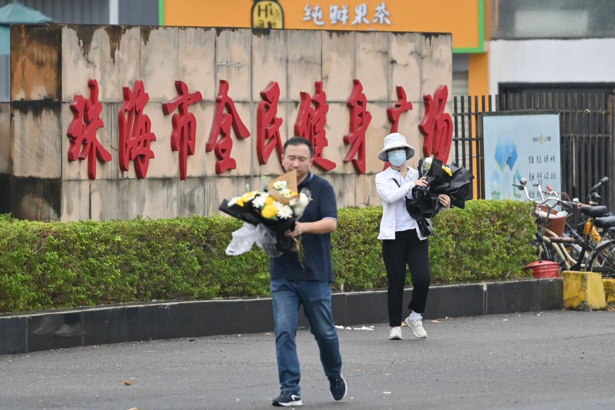 Workers remove flowers from a makeshift memorial outside the Zhuhai Sports Centre in Zhuhai in south China's Guangdong province on Nov. 13, 2024. (Hector Retamal/AFP via Getty Images)