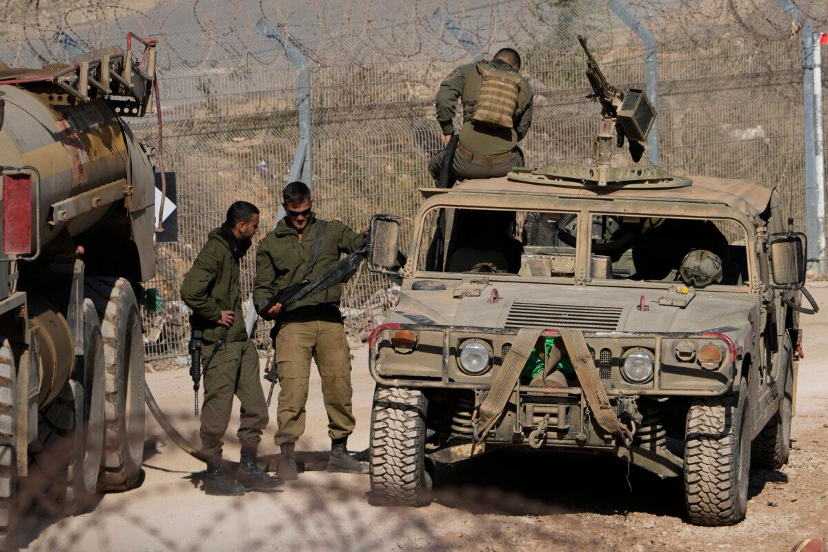 Israeli soldiers stand next to armored vehicles after crossing the security fence near the so-called Alpha Line that separates the Israeli-controlled Golan Heights from Syria, in the town of Majdal Shams, on Dec. 17, 2024. (Matias Delacroix/AP Photo)