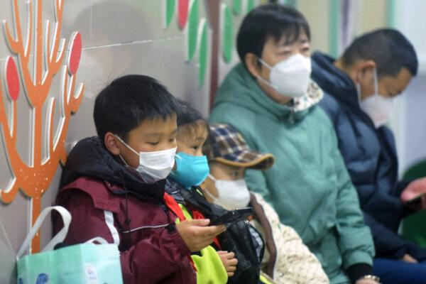 Masked children, accompanied by adults, wait to be seen by medical staff at the pediatric department of a hospital in Hangzhou, in eastern China's Zhejiang Province, on Jan. 6, 2025. (AFP via Getty Images)
