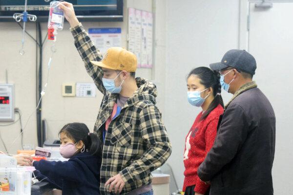 A family member (2nd L) holds an IV drip for a child (L) receiving care at the pediatric department of a hospital in Hangzhou, eastern Zhejiang Province, China, on Jan. 6, 2025. Beijing has acknowledged a surge in cases of the flu-like human metapneumovirus (HMPV), especially among children, and attributed it to a seasonal spike. (AFP/Getty Images)