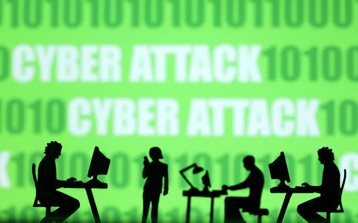 Miniatures of people with computers in front of binary codes and words "Cyber attack" in this illustration taken on July 19, 2023. (Dado Ruvic/Illustration/Reuters)