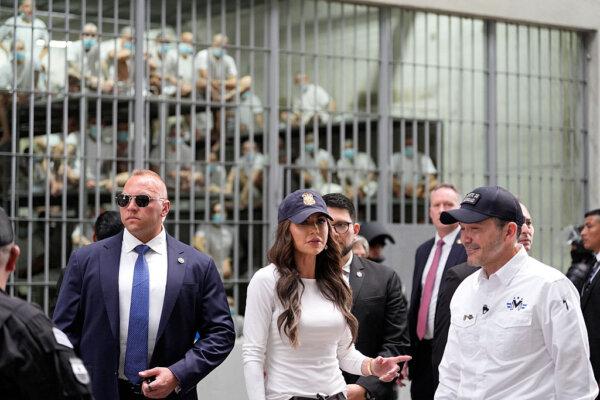 Prisoners watch behind bars as U.S. Secretary of Homeland Security Kristi Noem, accompanied by Minister of Justice and Public Security Gustavo Villatoro (R), tours the Terrorist Confinement Center in Tecoluca, El Salvador, on March 26, 2025. (Alex Brandon/Pool/AFP via Getty Images)