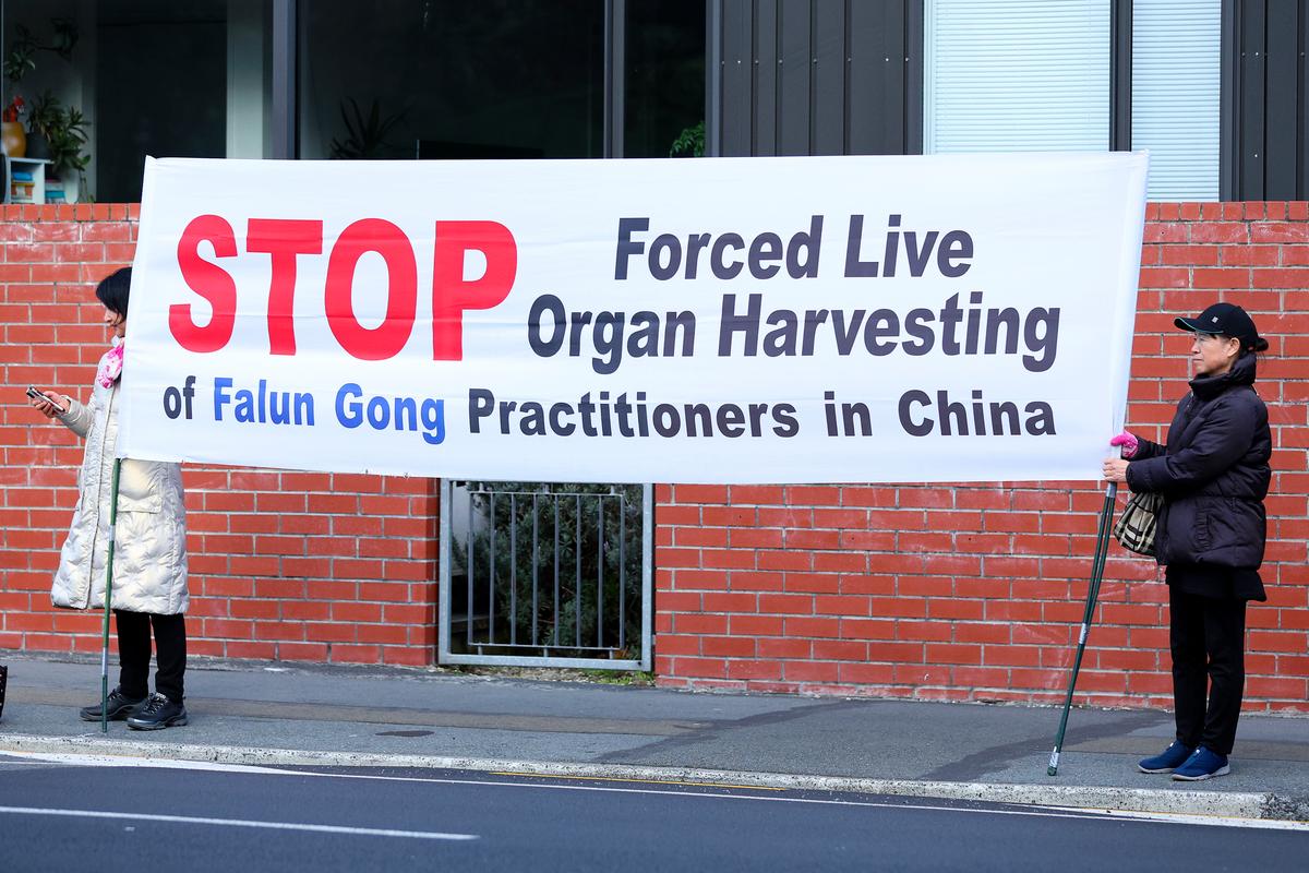 Protesters hold a banner outside Government House prior to an official welcome ceremony for CCP Premier Li Qiang in Wellington, New Zealand, on June 13, 2024. (Hagen Hopkins/Getty Images)
