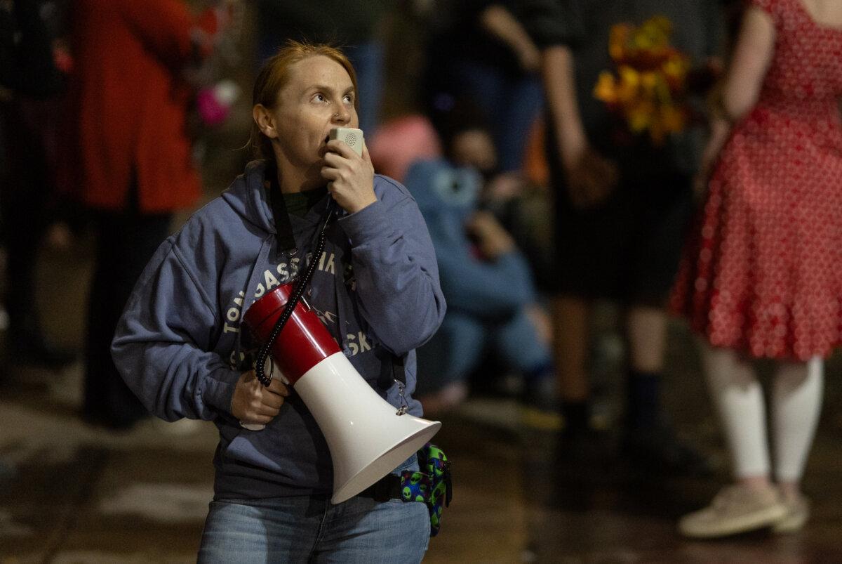 A woman shouts into a megaphone in front of Immigration and Customs Enforcement offices in Portland, Ore., on Oct. 4, 2025. (John Fredricks/The Epoch Times)