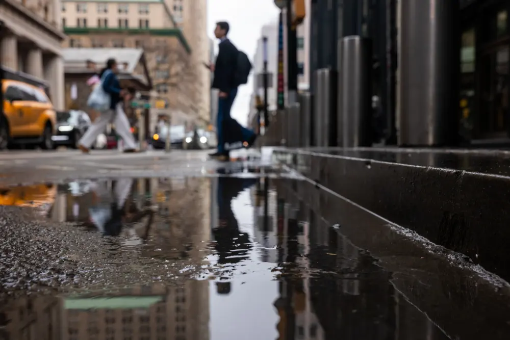 A pedestrian is reflected in a puddle as fog and in New York City on March 16, 2026. (Spencer Platt/Getty Images)