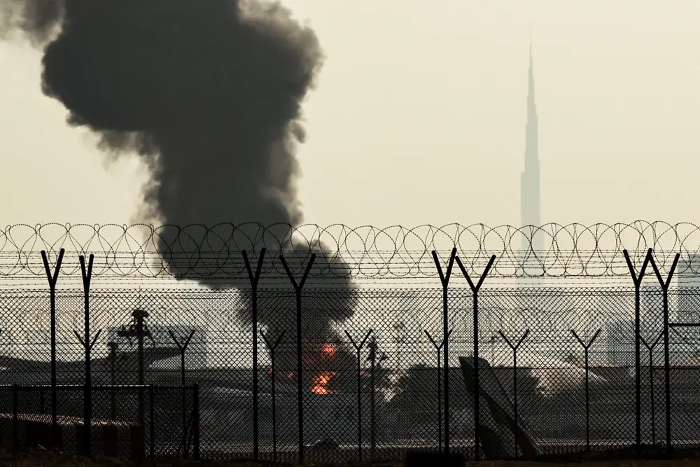 The Dubai skyline with the landmark Burj Khalifa skyscraper (R) is pictured as a smoke plume rises from an ongoing fire near Dubai International Airport on March 16, 2026. (AFP via Getty Images)