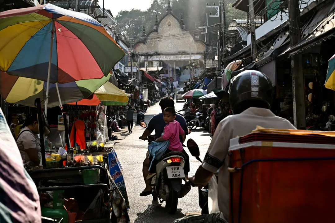 TOPSHOT - A boy sits on the back of a motorbike at a market along the Thai-Myanmar border in Mae Sai in the northern Thai province of Chiang Rai on March 17, 2026. (Photo by Lillian SUWANRUMPHA / AFP via Getty Images)