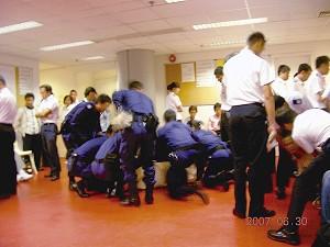A Falun Gong adherent is being wrapped up in a police blanket by several policemen at the Hong Kong International Airport last weekend. In the right hand corner, a policeman is trying to pull a female adherent. (Epoch Times)
