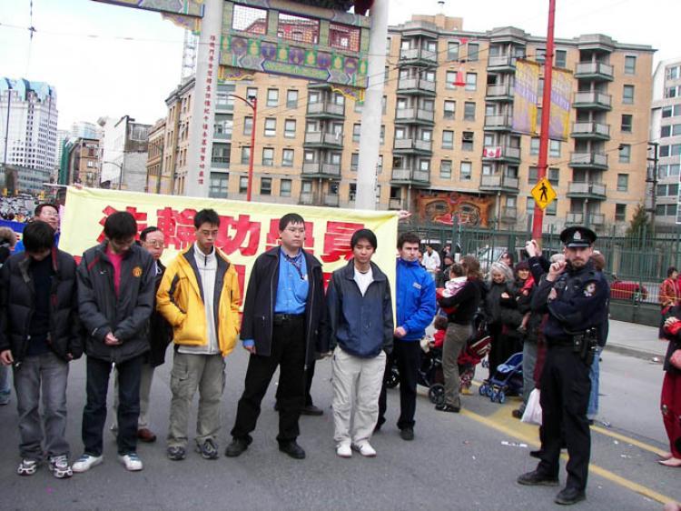 Several men form a human barrier to prevent the Falun Gong from marching a block behind the 2009 Chinatown parade. The group's application to join the parade has been denied every year since 2003 while other groups have been accepted. (The Epoch Times)