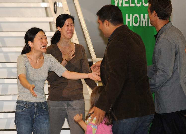 Freed U.S. journalists Euna Lee (L) and Laura Ling (2nd L) tearfully greet their husbands Michael Saldate (3rd L) and Iain Clayton (4th L) after being released from North Korea, at Burbank Airport, CA. on Aug. 5. (Robyn Beck/AFP/Getty Images)