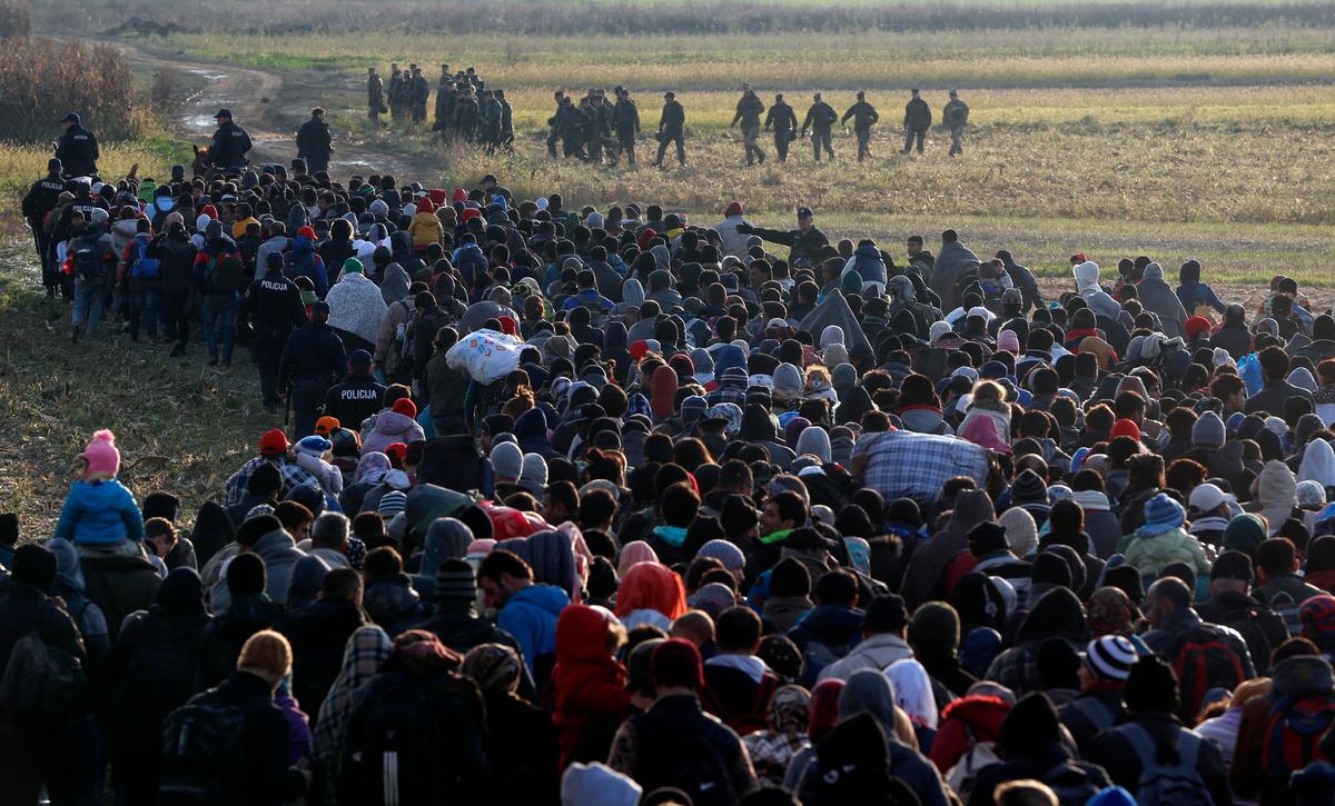 Migrants make their way toward a group of Slovenian soldiers after crossing from Croatia, in Dobova, near a border crossing between Croatia and Slovenia Wednesday, Oct. 21, 2015. A massive influx of migrants has increased tensions in the Balkans, which saw years of war in 1990s. Tense Balkan neighbors have been accusing each other of mishandling the flow of hundreds of thousands of people through the region toward Western Europe. (AP Photo/Darko Bandic)