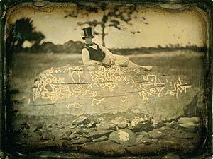 An 1853 reversed image of Seth Eastman (known for documenting Native American life in the 1800s) on top of the boulder known as Dighton Rock. (<a href="https://commons.wikimedia.org/wiki/File:Seth_Eastman_on_Dighton_Rock.jpg" target="_blank">Public Domain</a>)