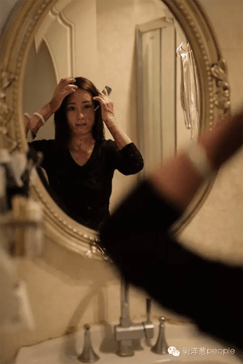 An adult Zhou Yan looks herself in the mirror (via Beijing News)