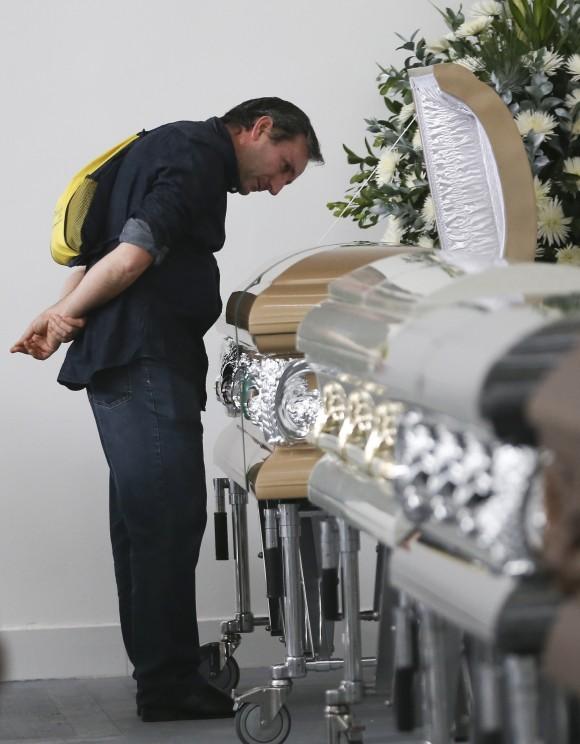 Roberto D'marchi gazes into the casket containing the remains of his cousin of Nilson Folle Jr., a victim of the Colombian air tragedy, in the parking garage of the San Vicente funeral home in Medellin, Colombia, on Dec. 1, 2016. (AP Photo/Fernando Vergara)