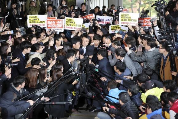 In this file photo, Choi Soon-sil, wearing a black cap at center, a longtime friend of South Korean President Park Geun-hye, is questioned by media upon her arrival at the Seoul Central District Prosecutors' Office in Seoul, South Korea. (AP Photo/Lee Jin-man, File).