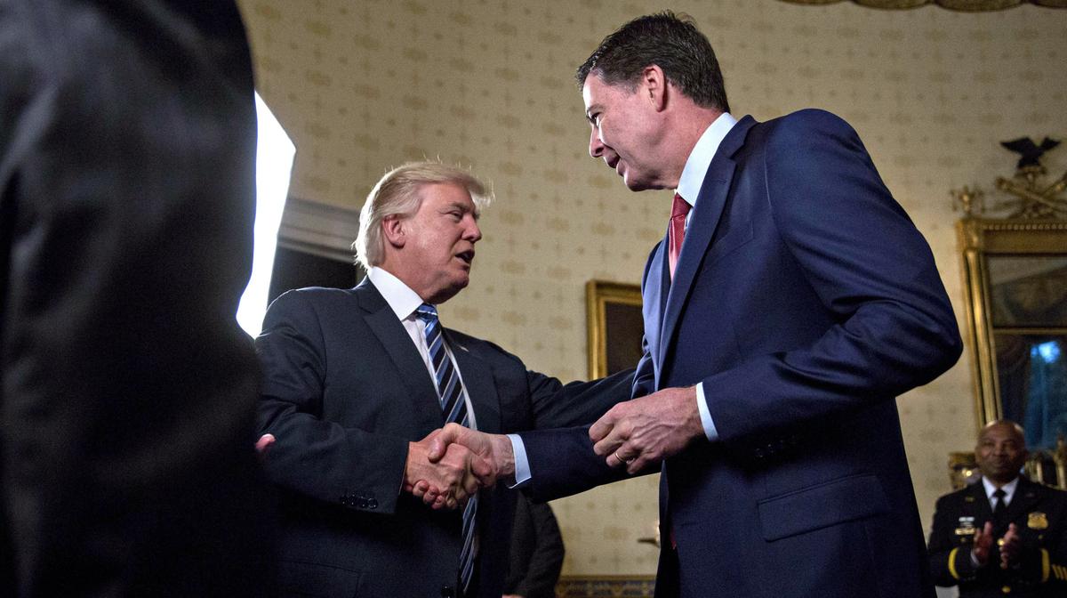 President Donald Trump (C) shakes hands with James Comey, director of the Federal Bureau of Investigation (FBI), during an Inaugural Law Enforcement Officers and First Responders Reception in the Blue Room of the White House in Washington, DC on Jan. 22, 2017. (Andrew Harrer-Pool/Getty Images)