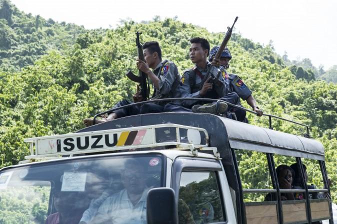 Burmese police sit on the roof of a truck as they provide protection for staff from the United Nations (UN) and International Non-Governmental Organizations (INGOs) after a visit to a conflict area, at a check point near the entrance of Maungdaw township in Burma's Rakhine State on Aug. 28, 2017. (STR/AFP/Getty Images)