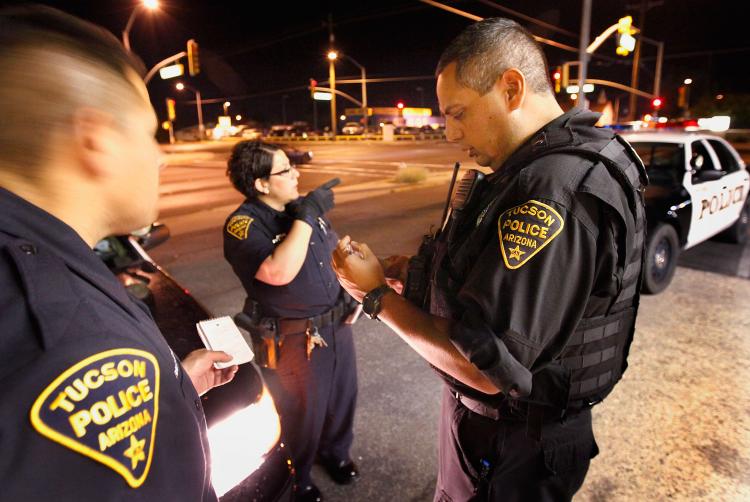 Leon Gutierrez (R), of the Tucson Police Department's Gang Tactical Unit, assists patrol officers Luis Hernandez (L) and Jessica Stoneham who were responding to a fight June 3, 2010 in Tucson, Arizona. (Scott Olson/Getty Images)