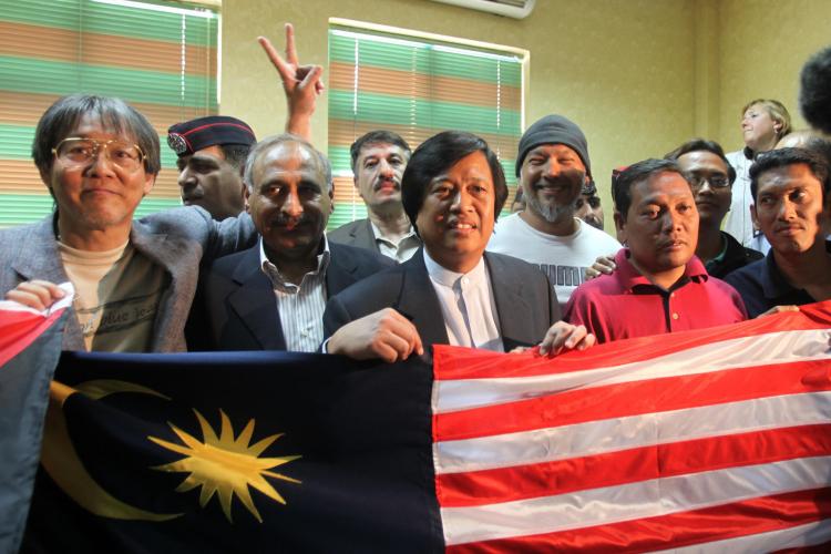 Activists who were aboard the Rachel Corrie aid ship, which tried to run the Israeli blockade of Gaza, pose behind a Malaysian flag as they cross into Jordan on June 6, following their expulsion from Israel.  (Khalil Mazraawi/Getty Images)