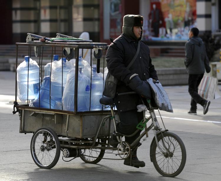 A worker cycles with mineral water for delivery in a street in downtown Beijing on December 29, 2010. The quality of China's tap water was raised on World Water Day. Reports and statements by professionals all point to a drinking water crisis.  (Liu Jin/Getty Images )