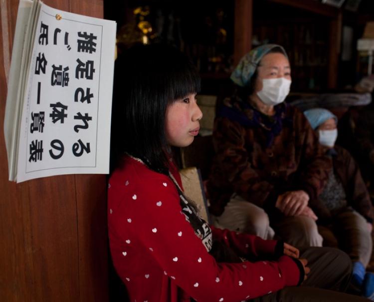 A list of names of earthquake and tsunami victims hangs on a wall as Japanese refugees wait for aid at a Buddist temple used as an evacuation centre in Ofunato, Iwate prefecture on April 4, 2011.  (Yasuyoshi Chiba/Getty Images)